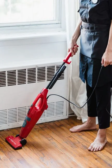 Cleaner using a vacuum in a stylish indoor setting, showcasing cleaning equipment and techniques.